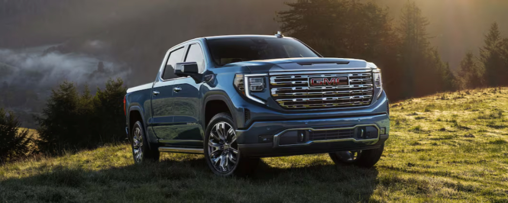 blue 2025 GMC Sierra 1500 driving up a grassy hillside